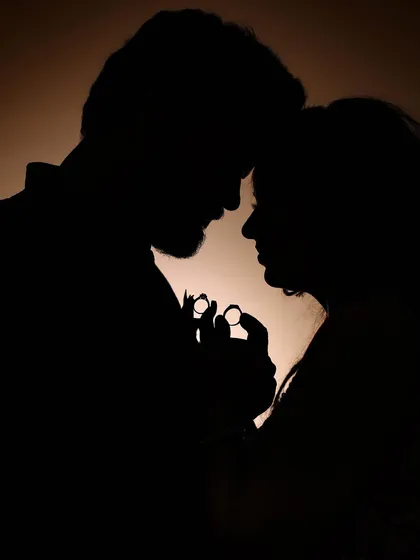 A powerful silhouette shot of a couple holding their engagement rings, creating a symbolic and artistic portrait.