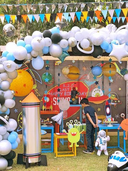 An out-of-this-world space-themed birthday party. The setup included a planet-filled backdrop, a rocket ship prop, and a massive balloon galaxy arch to launch the kids into a fun mission.