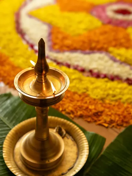 A traditional brass lamp, or 'vilakku', glowing warmly in front of a floral 'pookalam' for Onam. This image is close to my heart as it reflects my Kerala roots and my love for capturing the quiet, soulful moments of our festivals.