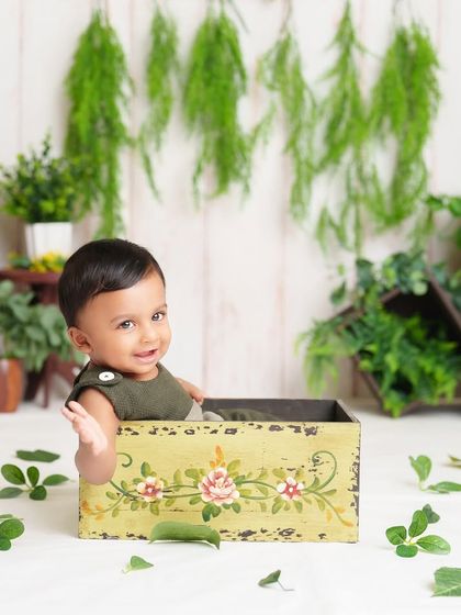 A happy wave from this little guy in a box. The simple green and white setup with natural elements creates a fresh and clean look for his milestone photos.