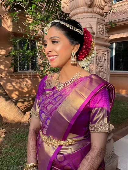 A side view capturing the complete look, including the traditional floral hair arrangement. The makeup is balanced to look stunning from every angle, enhancing her natural grace.