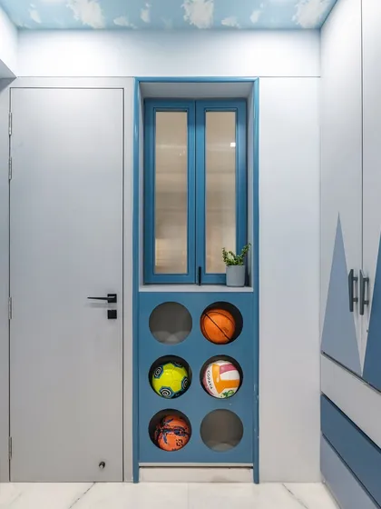 Smart storage is key in any kid's room. This custom-built unit in a calming blue finish features designated circular compartments for sports balls, keeping them organized and easily accessible while adding a playful, graphic element to the room's entryway.