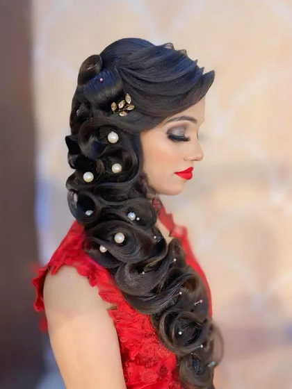 A side view of a dramatic, full bodied braid decorated with pearls and a delicate gold leaf accessory. This hairstyle is perfect for making a statement at an evening reception.
