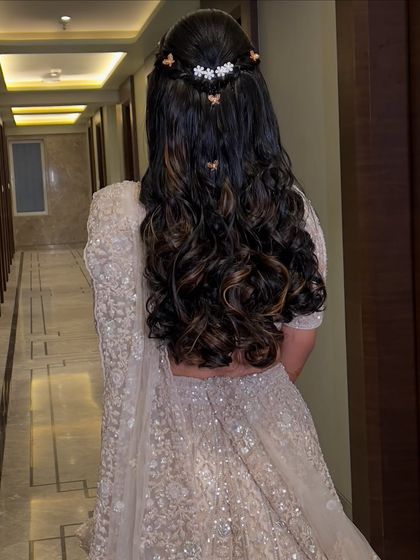 A modern reception hairstyle with soft curls and butterfly clips, perfect for a contemporary lehenga.