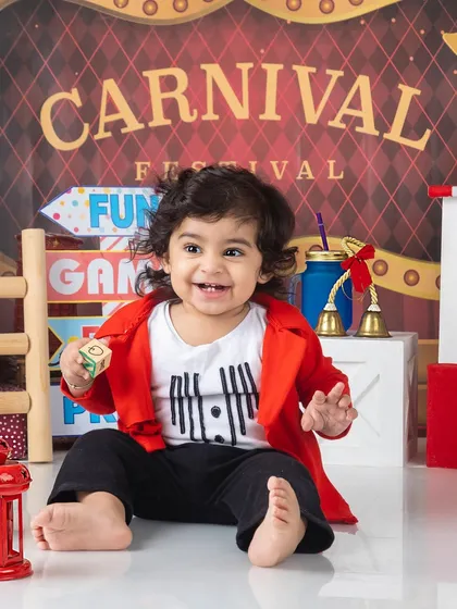 A happy baby boy enjoying the fun and games at his carnival-themed photoshoot.