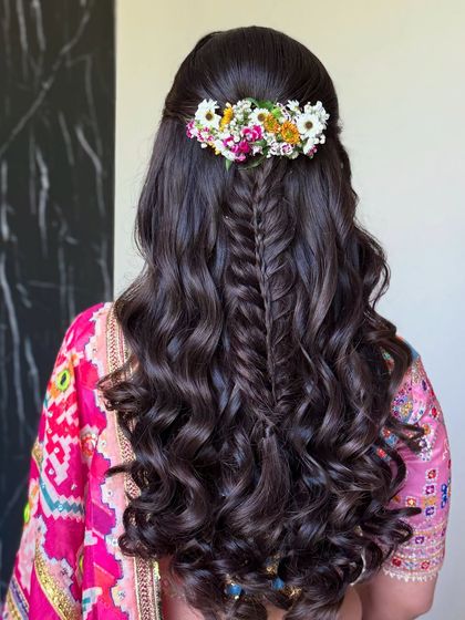The final look: a half-up style with a fishtail braid, voluminous curls, and a vibrant floral arrangement.