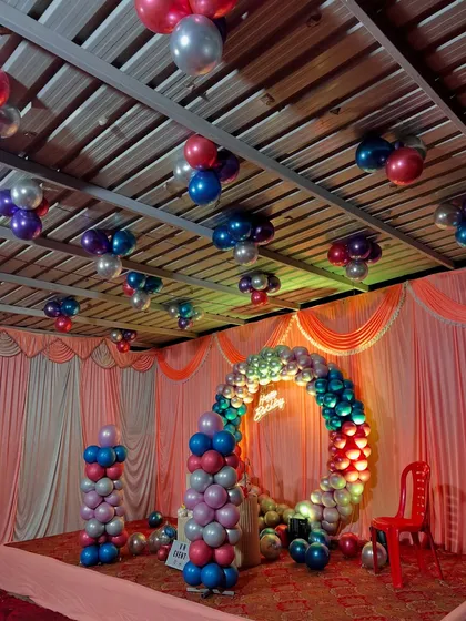 A full-room birthday decoration with a colorful theme. We created a circular balloon arch for the stage and added matching balloon bunches to the ceiling for a complete party look.
