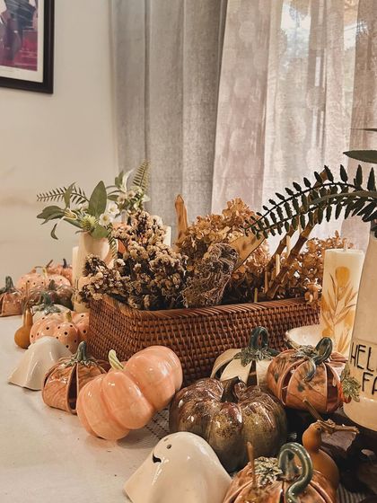 A wide shot of my autumn tablescape, complete with ceramic pumpkins, friendly ghosts, dried flowers, and candles. It's everything I love about this cozy season.