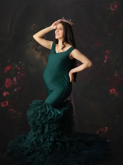 A candid moment of joy captured in a stunning emerald green ruffled gown. The dark floral backdrop adds a touch of romance to this powerful and happy portrait.