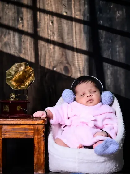 This shot uses dramatic lighting to create a vintage mood. The newborn, dressed in a cozy robe, looks like a tiny music aficionado enjoying a quiet moment.