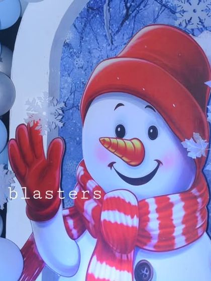 A friendly snowman cutout greets guests at a winter-themed party, set against a backdrop of blue and silver balloons.