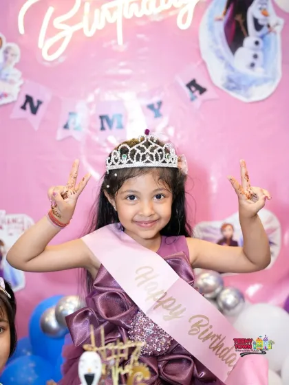 The birthday girl feeling like royalty with her tiara and sash at her Frozen-themed celebration.