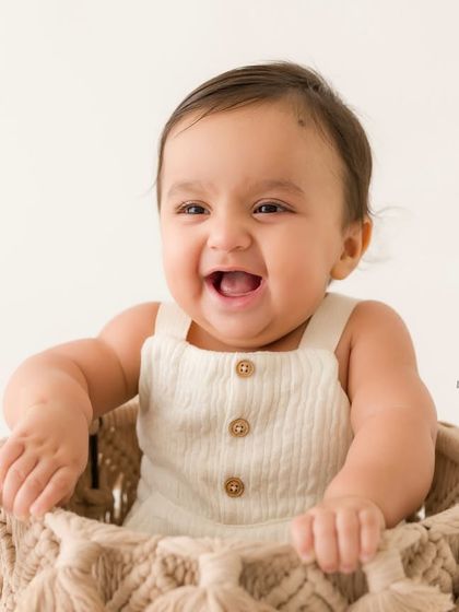 A bucket of joy! This happy baby is all smiles while sitting in a woven macrame basket, a fun and popular prop for sitter sessions.