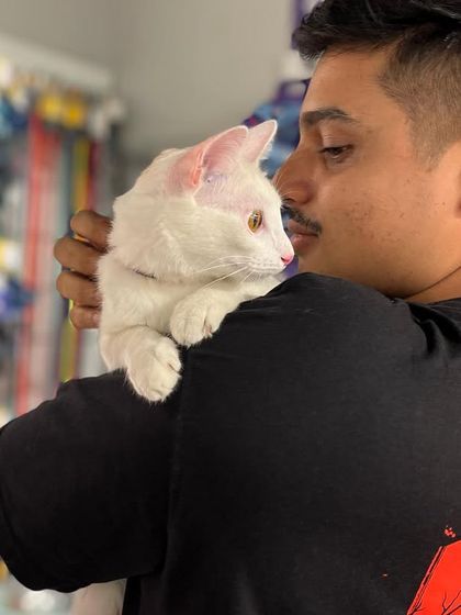 A volunteer holds a beautiful white cat at a HUFT adoption camp. Our volunteers are the backbone of our organization, giving their time and love to the animals.