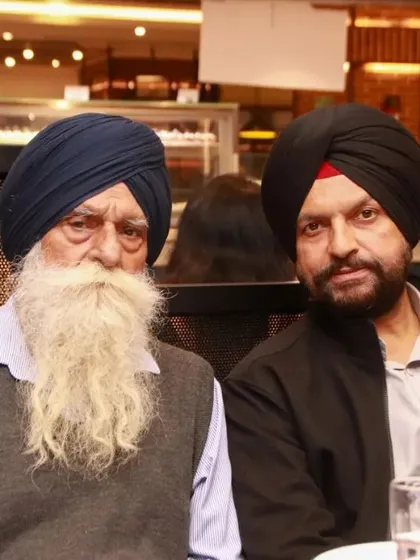 A portrait of two elderly Sikh gentlemen with impressive beards, seated together at a family gathering. We respectfully capture portraits of all your guests.