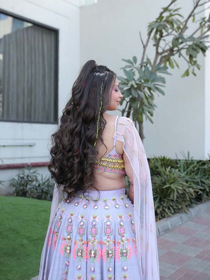 A side view of the carnival hairstyle, showing the height of the half-ponytail and the beautiful cascade of curls. This style is all about volume and movement.