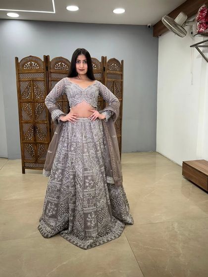 This full-length shot showcases a stunning grey lehenga with intricate white embroidery. It's a chic and modern choice for any wedding event.
