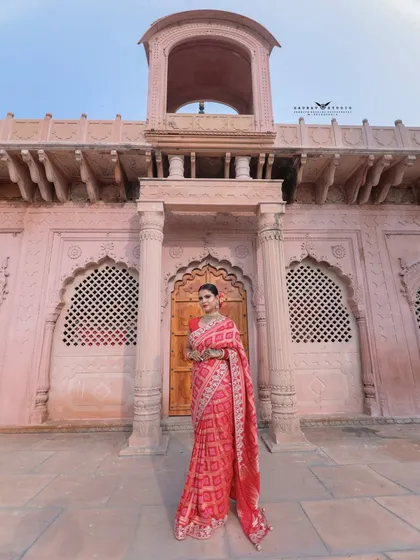 A wide shot showing the model against the grand facade of the pink heritage building.