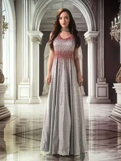 A grand palace hall, projected as a backdrop, lends a sense of scale and majesty. The lighting is kept soft and even to highlight the delicate details of the gown.