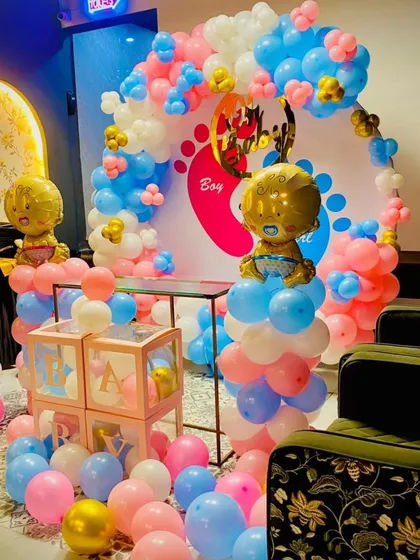 A fun and festive baby shower setup with a "Boy or Girl" theme. The decoration includes a balloon arch, 'BABY' blocks, and large foil baby balloons, creating a perfect photo corner for the celebration.
