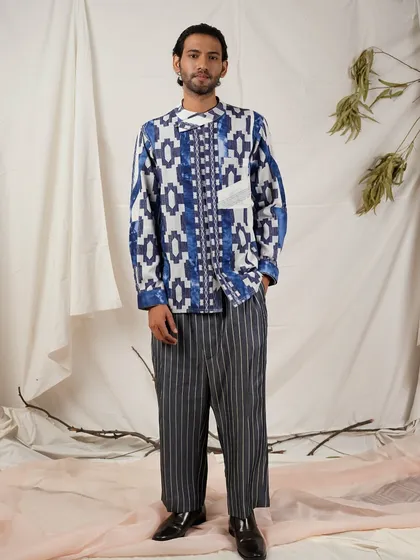 A full-length view of the geometric print shirt paired with pinstripe trousers. This lookbook image shows customers how to style the piece for a complete, fashion-forward outfit.