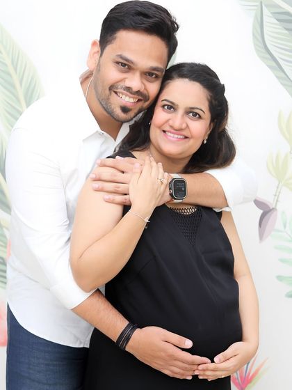 A happy, relaxed portrait of a couple looking directly at the camera. His arms wrapped around her from behind is a classic, loving pose that always results in genuine smiles.