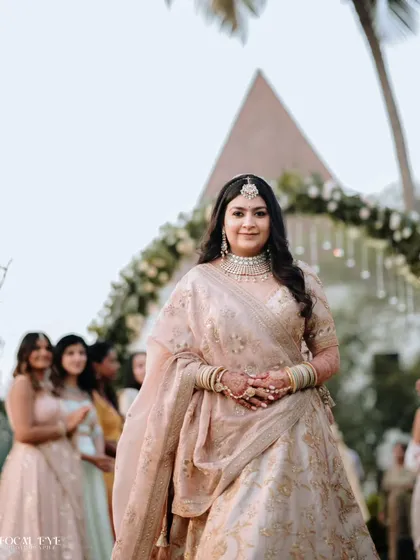 A portrait of the bride as she walks down the aisle, with her bridesmaids visible in the background.