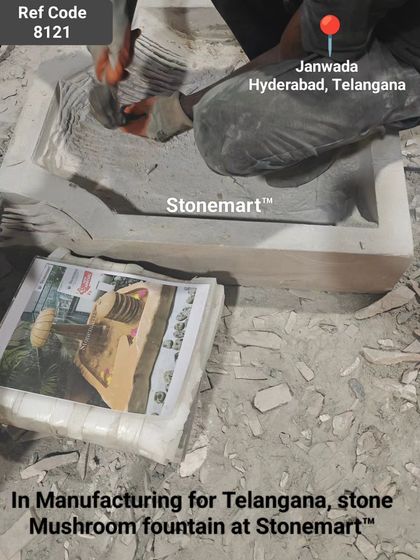 An artisan carves the basin of the mushroom fountain, following a design template.