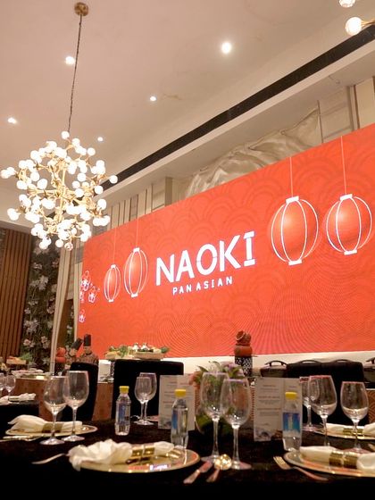 A beautifully set table at our "Naoki" pop-up, with branded menus and elegant glassware, all under the warm glow of modern chandeliers.