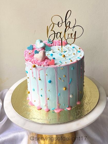 A sweet "Oh Baby" shower cake with a pink and blue drip, representing a gender reveal. The hearts and sprinkles add a playful touch.