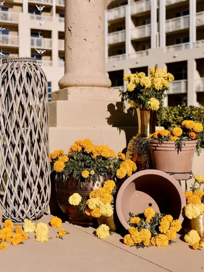 The wedding decor featuring pots of bright yellow marigolds, a detail that was reflected in the color palette and floral motifs of the 'Manglik Prasang' invitation card.