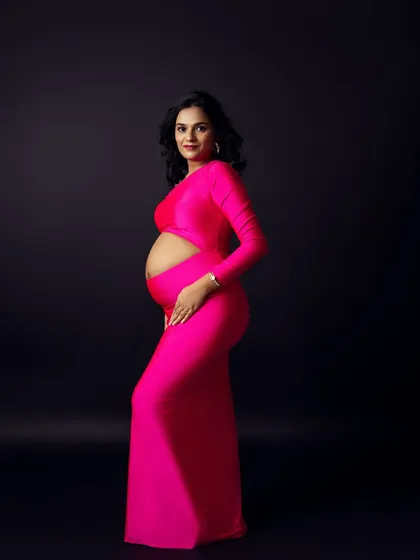 A bold and modern solo portrait in a vibrant, hot pink gown against a classic black background.