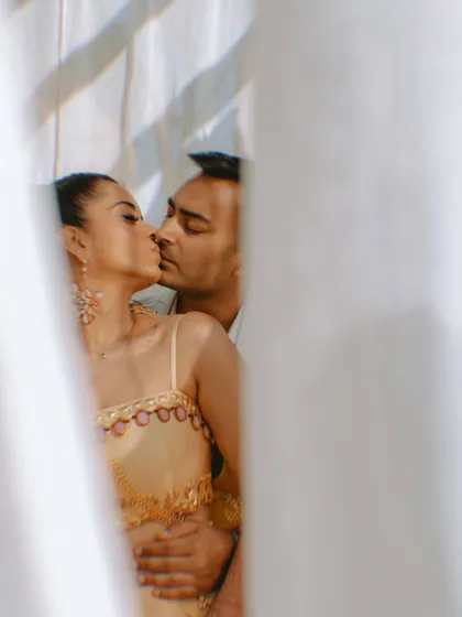 A passionate and romantic moment between the couple, captured artistically through a sheer curtain.