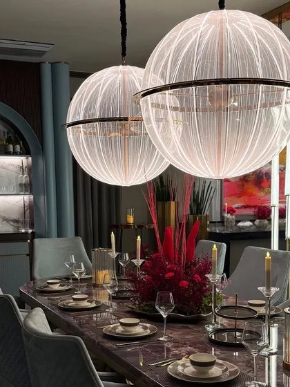 A luxurious dining room setup featuring a dramatic floral centerpiece and stunning globe pendant lights. We work to enhance the existing beauty of a space.