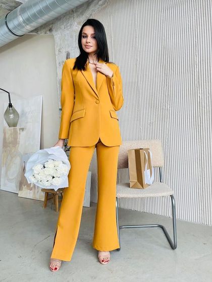 This single-breasted suit in a warm mustard yellow features unique side slits on the bootcut trousers, adding a modern touch to a classic design.