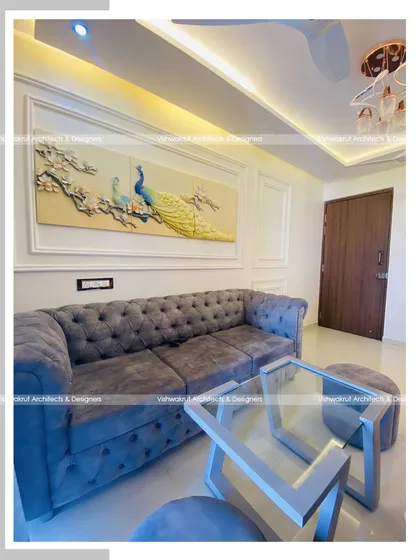 This photo highlights the seating area of the living room, with a plush grey tufted sofa set against a wall with elegant molding and a beautiful peacock art piece. The design creates a sense of quiet luxury.