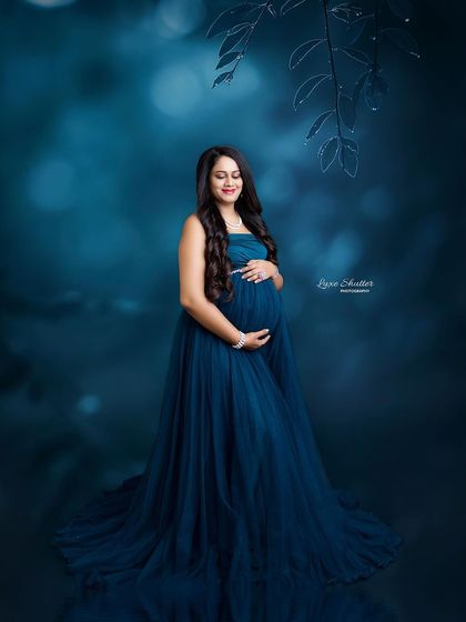 A serene portrait in a flowing teal gown. The moody, artistic background with soft bokeh gives the image a dreamy, underwater feel.