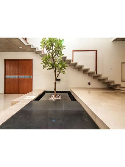 An indoor water body and a central tree create a serene focal point in the Cube Square residence. This biophilic design element brings the calming qualities of nature indoors.