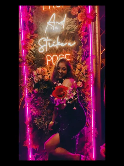 All eyes on me. Striking a pose at a party with a cool neon sign. A sparkly dress is perfect for a night of fun and celebration.