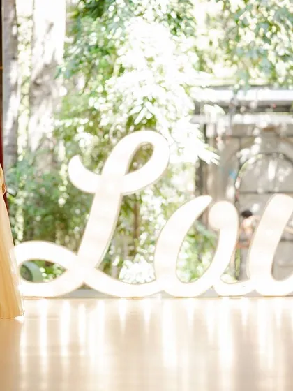 A maternity shoot with the large, illuminated 'Love' sign, celebrating the love that is growing the family.