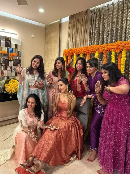 A fun group photo from a sangeet, with the bride and her bridesmaids all showing off their beautiful party mehndi.