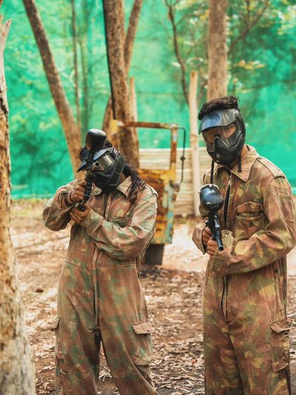 Two players in full camouflage and protective gear, ready for a game of paintball in our forest arena.