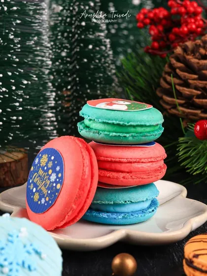 Another angle of the festive macarons, focusing on their vibrant red and green colours against the dark, moody background.
