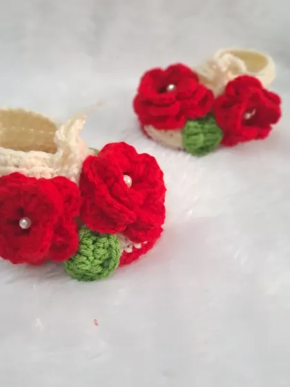 These off-white booties are decorated with vibrant red crochet roses, making for a striking and beautiful contrast.