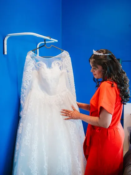 The bride admires her beautiful white wedding gown before getting dressed. Capturing these getting-ready details is part of telling the full story.