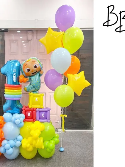 This Cocomelon birthday bouquet is perfect for a toddler's party. It features JJ, colorful building blocks, and a number '1' balloon, all in the bright, primary colors of the popular show.
