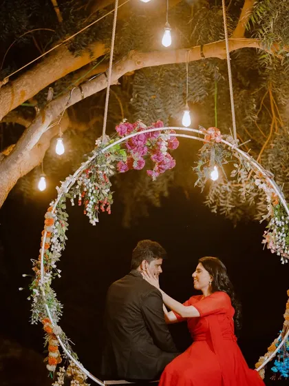 A whimsical and romantic shot on a decorated floral swing. The hanging lights create a beautiful bokeh effect, adding to the magical feel of this night-time pre-wedding photo.