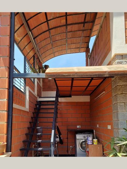 An external staircase and utility area, covered by a curved roof made of terracotta tiles, showing how even functional spaces can be beautifully designed.