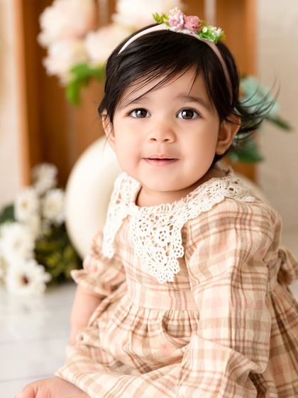 A close-up portrait of a smiling baby girl from her vintage-themed sitter session.
