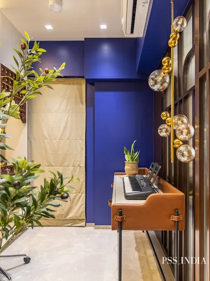 A stylish music corner featuring a keyboard on a leather-wrapped stand. The deep blue wall, bubble-like light fixture, and an olive tree create a chic and creative atmosphere.